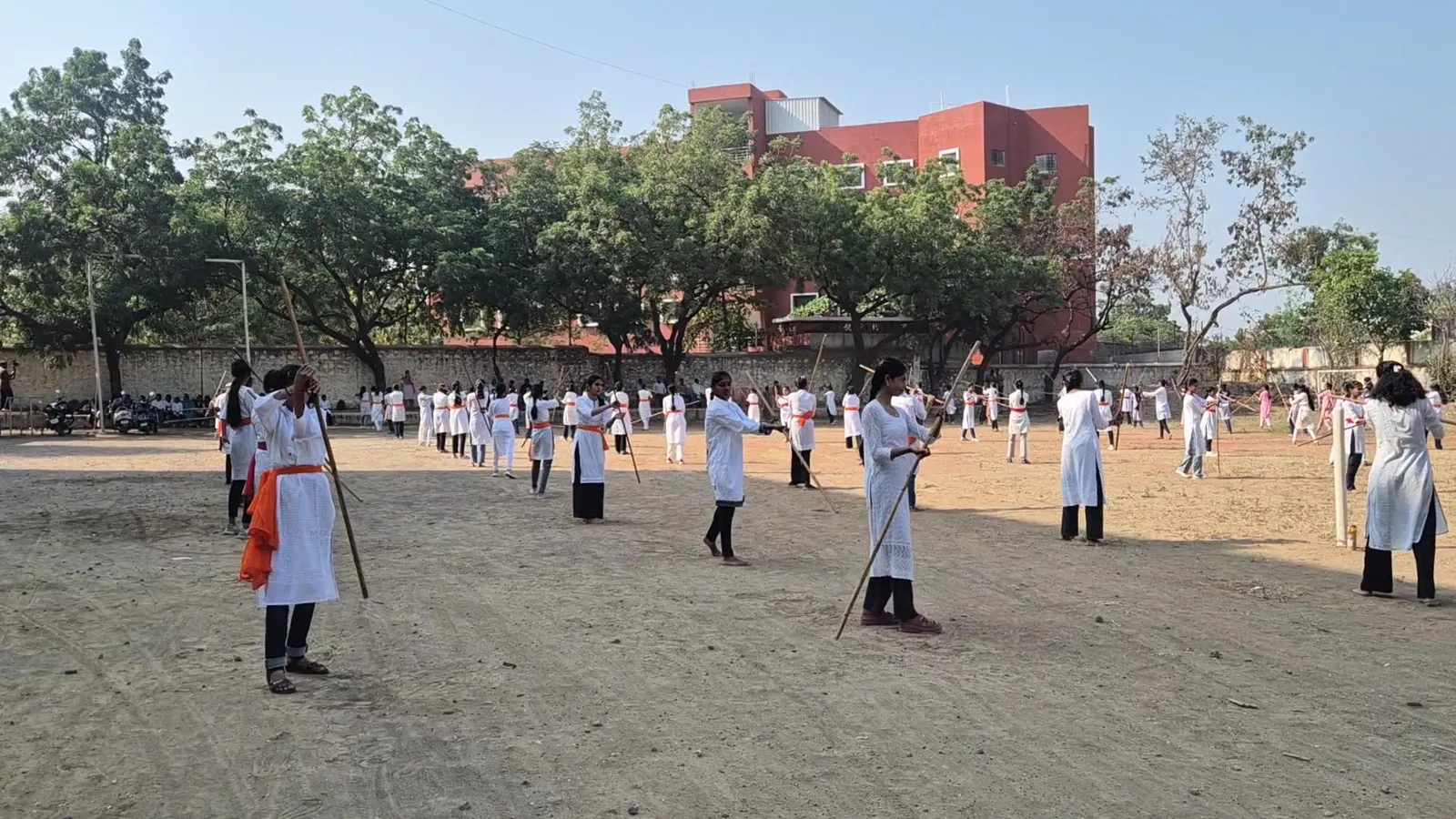 Girls in white uniform drilling with lathis at New Arts, Commerce and Science College, Shevgaon