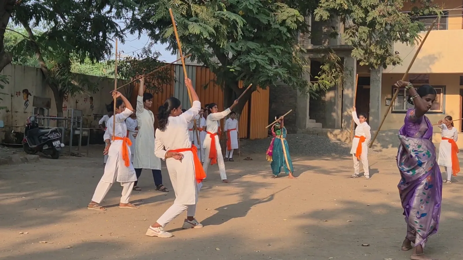 Two girls in white uniform with orange sashes in a Lathi Kathi bout